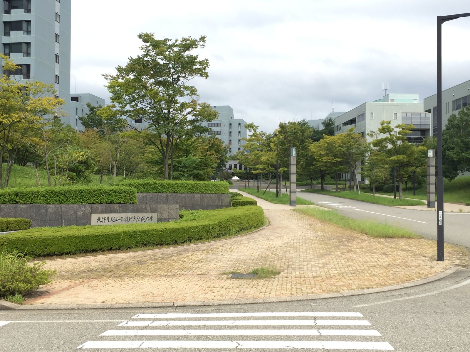 The entrance to the JAIST campus, with tree-lined paths and university buildings